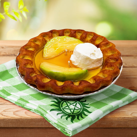 An 'apple pie' candle on a picnic table. The candle is in the shape of an apple pie, complete with 'crust', caramelized 'apple slices' on top, and a dollop of 'ice cream', in a 'pie tin' holder.