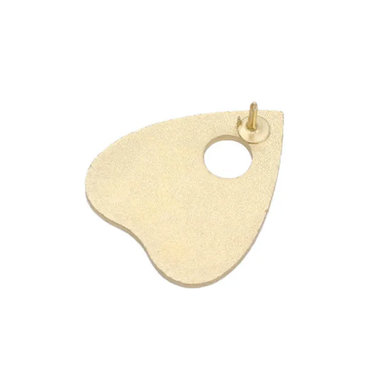 The gold backing of a planchette-shaped enamel pin against a white background.