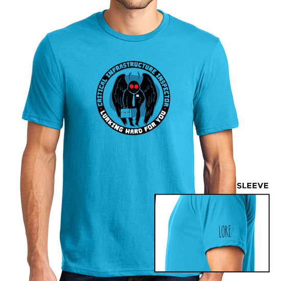 A male model wearing a turquoise, short-sleeved, crewneck tee. The tee has a black ring/circle printed with the words "Critical infrastructure inspector" in turquoise font and "Working hard for you" in white font. Within the ring is a black cartoon Mothman with red eyes, a turquoise tie, and a turqouise briefcase set against a darker shadow. One sleeve features the 'LORE' logo in black.