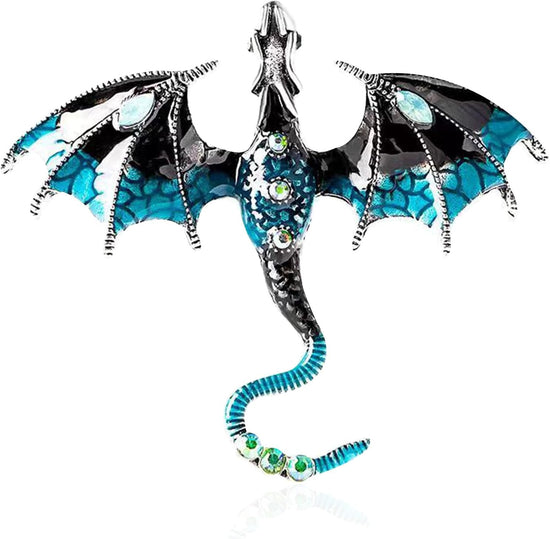 Close up view of a dragon-shaped brooch against a white background. The dragon is blue with silver accents, and has blue rhinestones inset in its tail and abdomen. The dragon's wings are spread out to the side, and its head is pointed straight out.