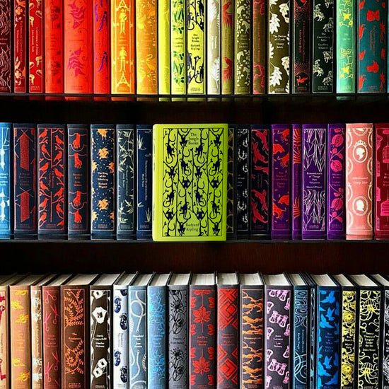Several rows of Penguin Clothbound Classic titles on a wooden bookshelf. In the center is a bright green book with a pattern of monkeys drawn across the cover. Text at the top says "The Jungle Books" Rudyard Kipling."