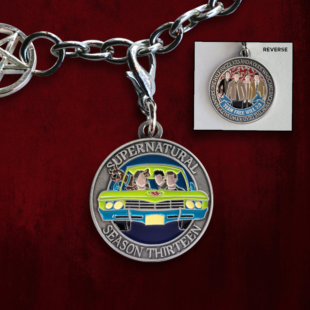 Front and back images of a brass charm, against a red background. The front depicts SPN characters in a green and blue car, with a dog out the window. Raised text around the edge says "supernatural season thirteen." The back depicts characters wearing brown jackets. Raised text says “Two salty hunters, one half-angel kid, and a dude who just came back from the dead. Team Free Will 2.0"