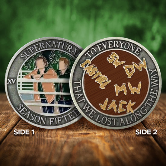 Front and back views of a brass coin. On the front is a depiction of Sam and Dean Winchester leaning on a white fence, with trees in the background. Around the edge of the coin, raised text says "Supernatural Season Fifteen.” The back of the coin depicts a wooden table with the names and initials of SPN characters carved into it. Around the edge is raised text saying “To everyone that we lost along the way.”