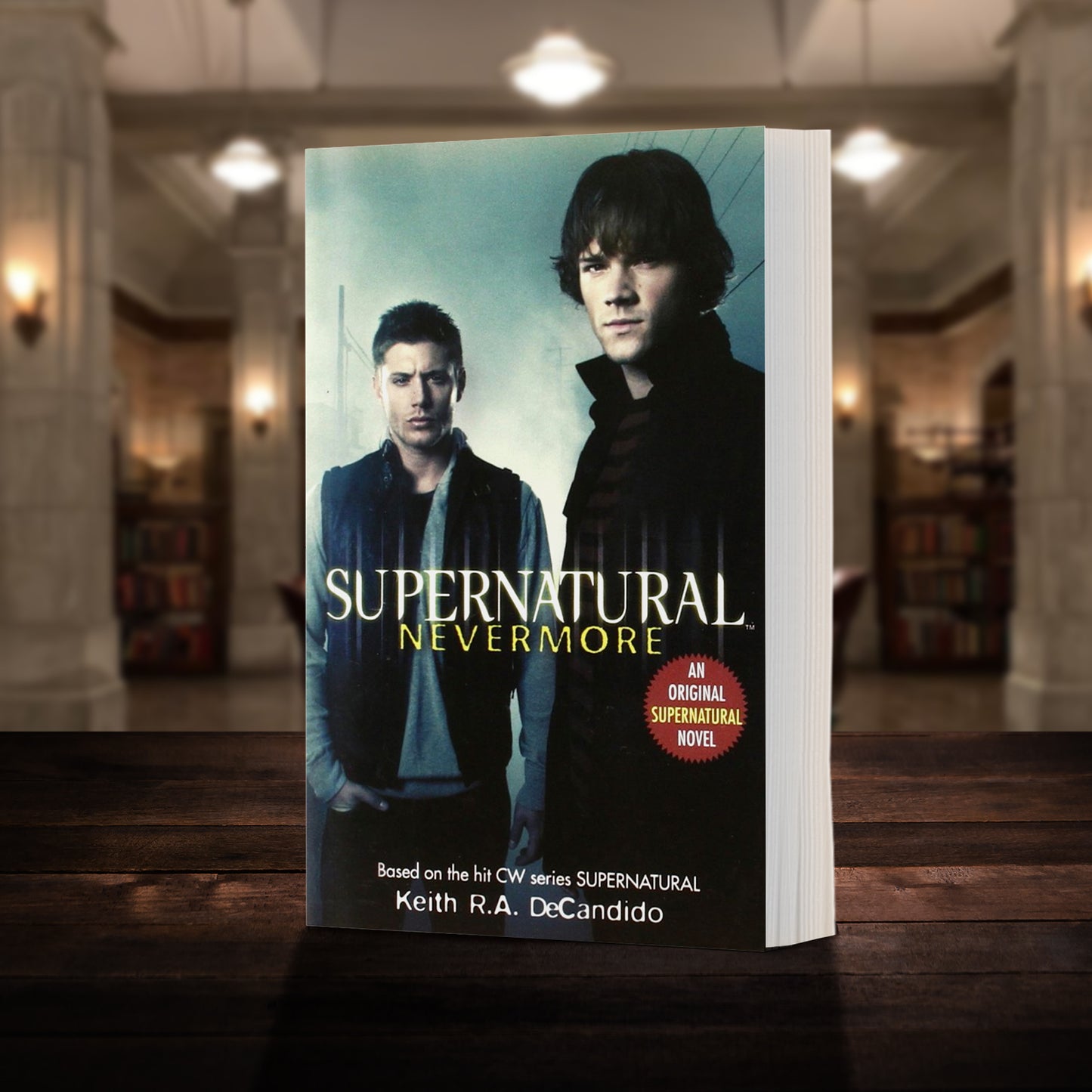 A copy of the book "Supernatural: Nevermore" as pictured in the "bunker" from Supernatural. The cover shows early-season Sam and Dean Winchester and reads "Supernatural Nevermore - Based on the hit CW series SUPERNATURAL by Keith R.A. DeCandido"
