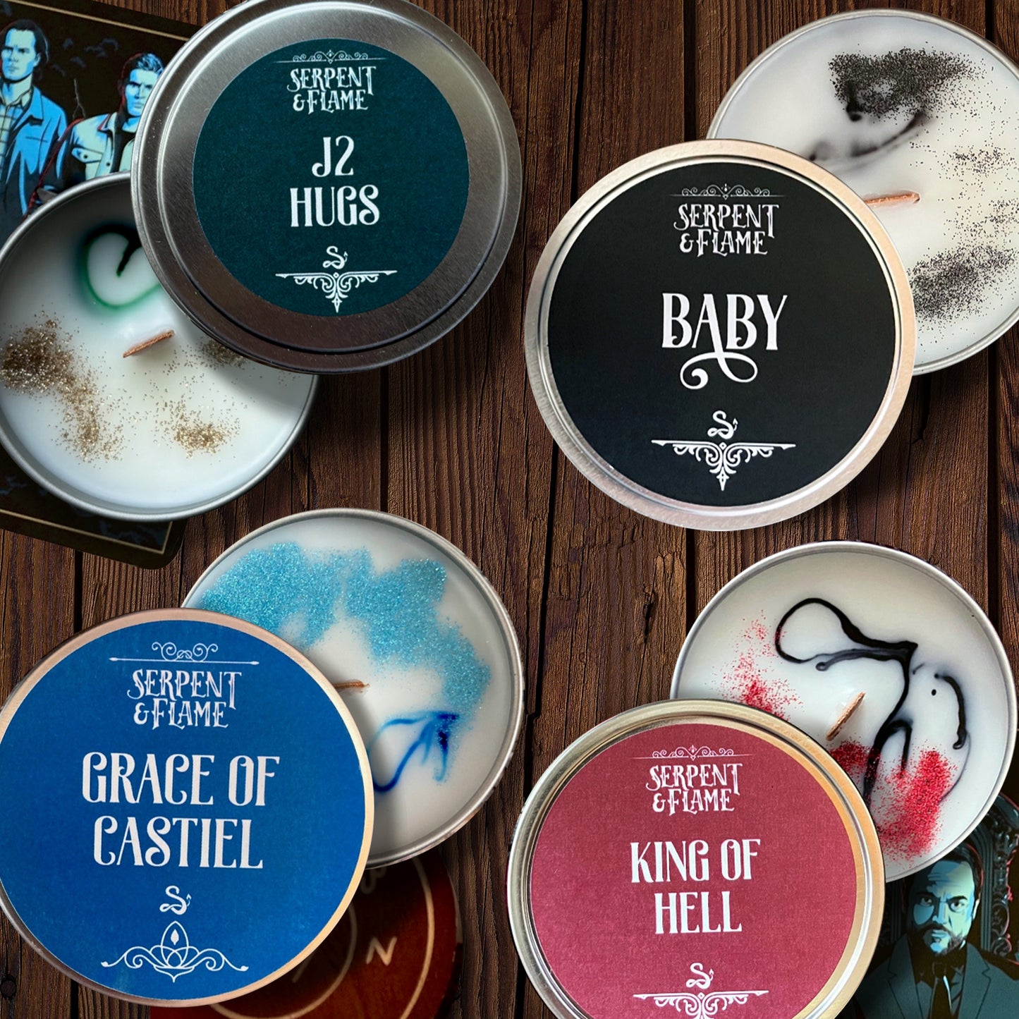 A collection of candle tins on a wooden table, each with a label with a reference to Supernatural on the top.