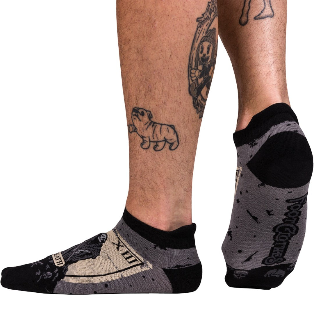 Black and gray socks worn on feet with tattoos visible on a white background
