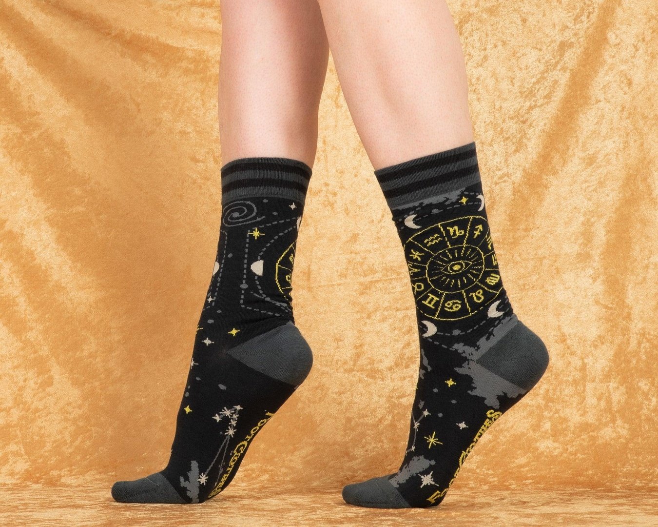 Black socks with star and moon patterns worn by a person on a beige background