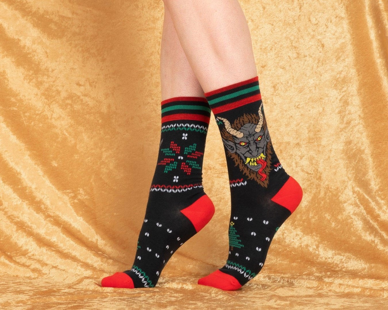 Colorful patterned socks worn on a gold fabric background