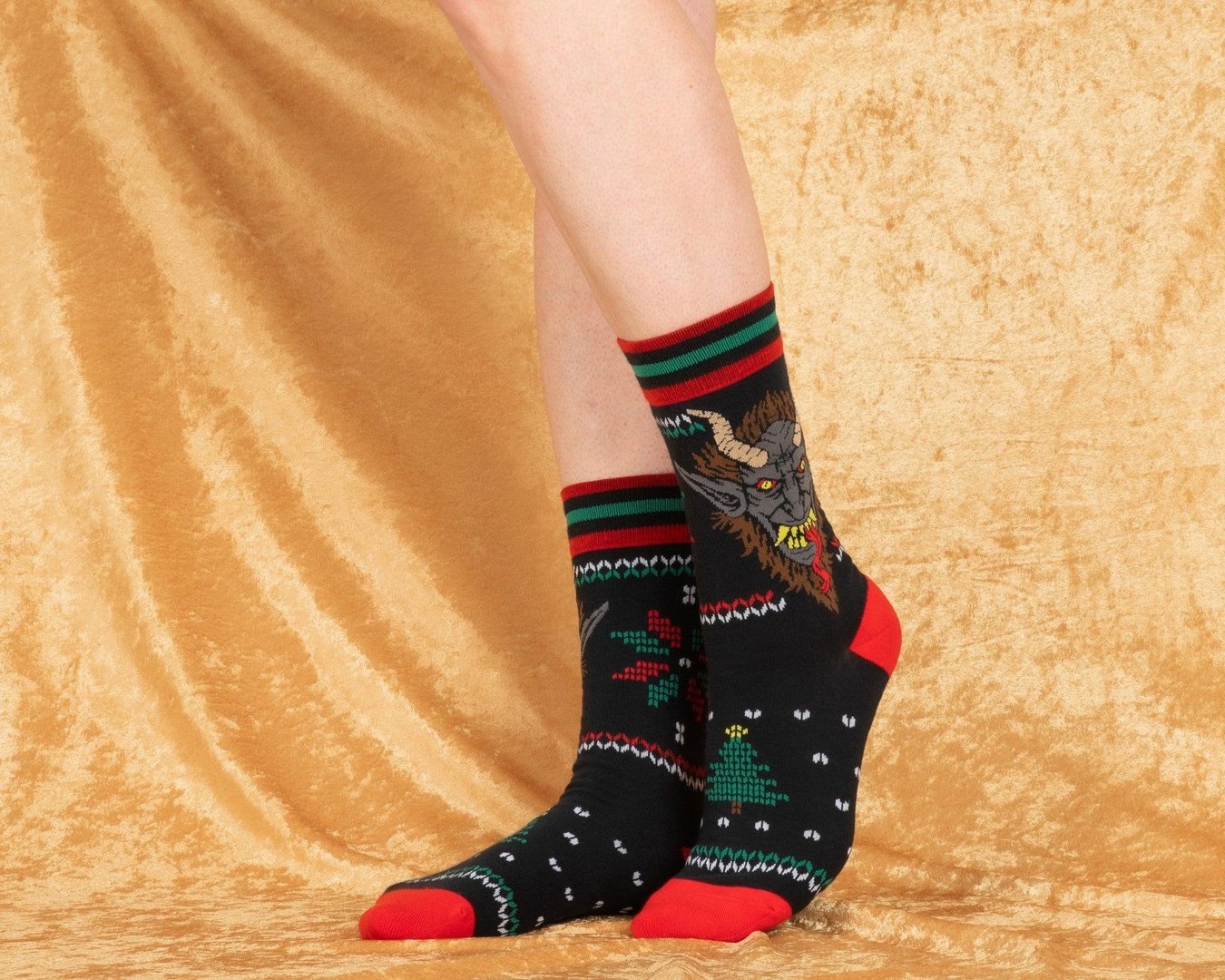 Black socks with colorful patterns worn by a person on a beige fabric background
