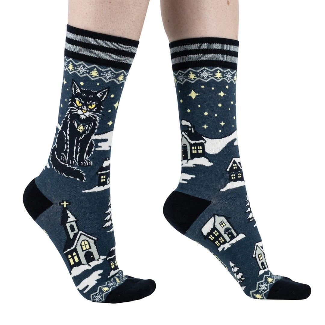 Socks with a winter-themed design featuring a cat, houses, and stars on a dark blue background.