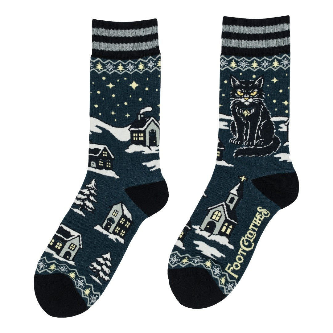 Pair of socks with winter-themed design featuring houses and a cat on a dark blue background.