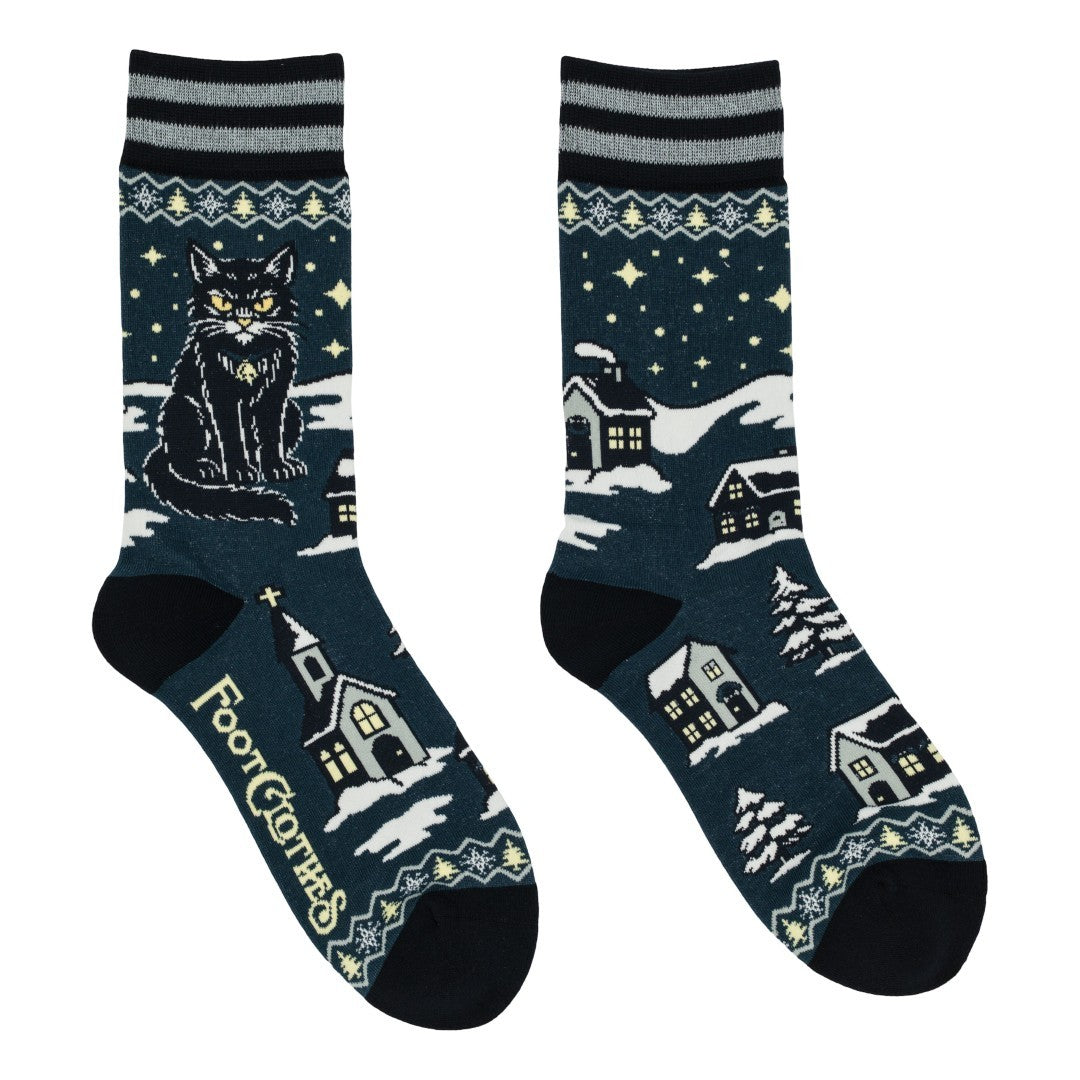 Pair of socks with winter-themed design featuring a cat and houses on a dark blue background.