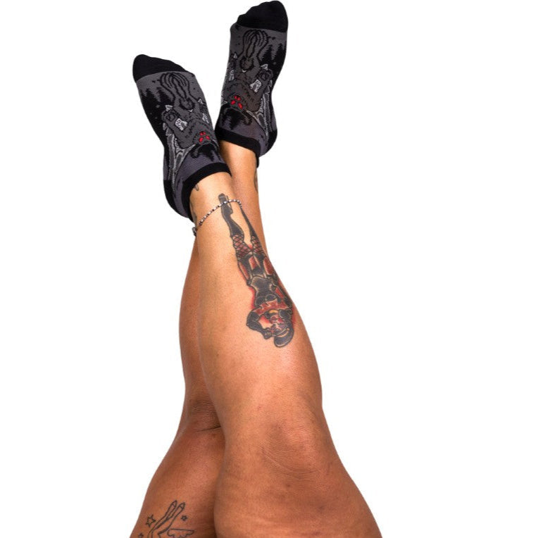 Black ankle socks with Mothman designs worn by a person on a white background