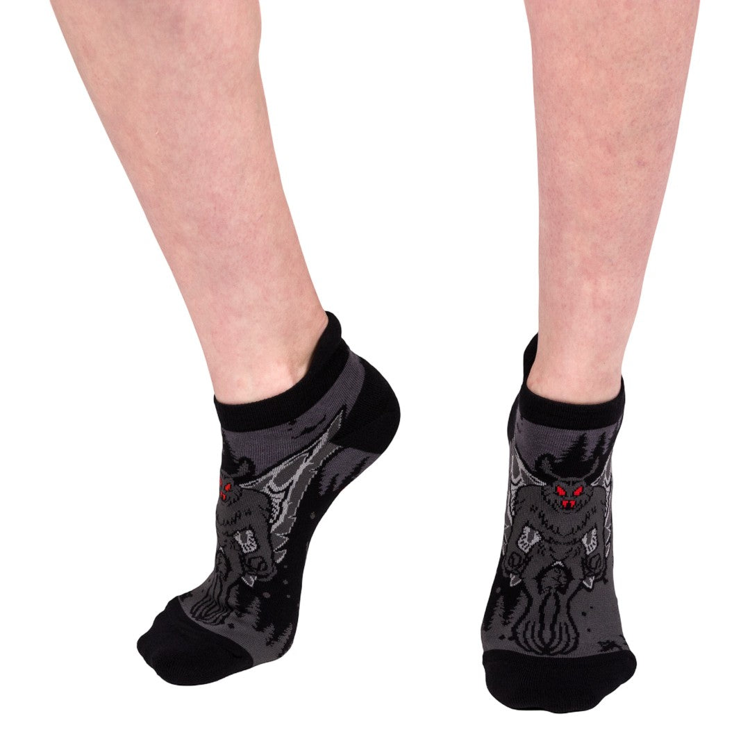 Black ankle socks with Mothman designs worn by a person on a white background