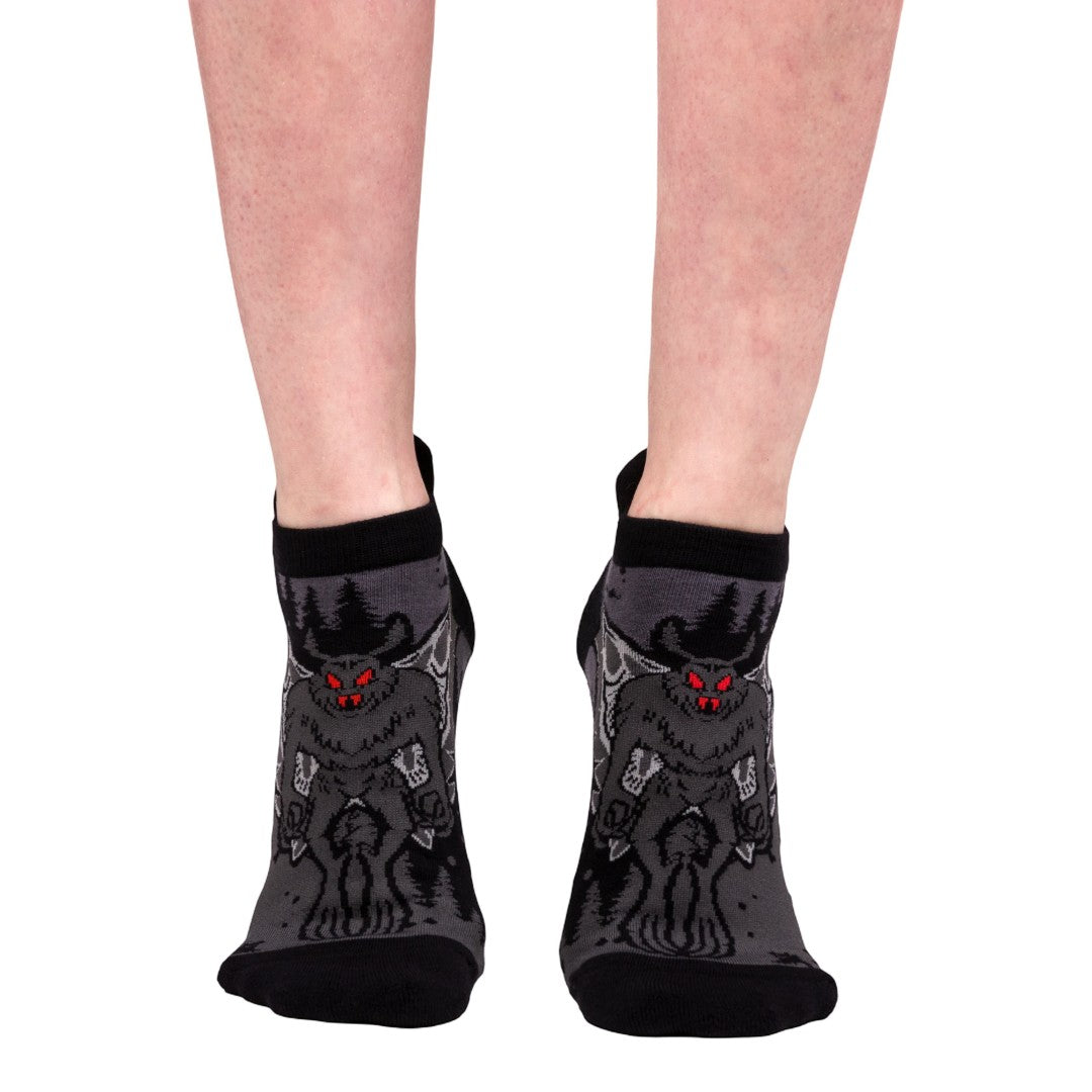 Black socks with Mothman design worn by a person on a white background