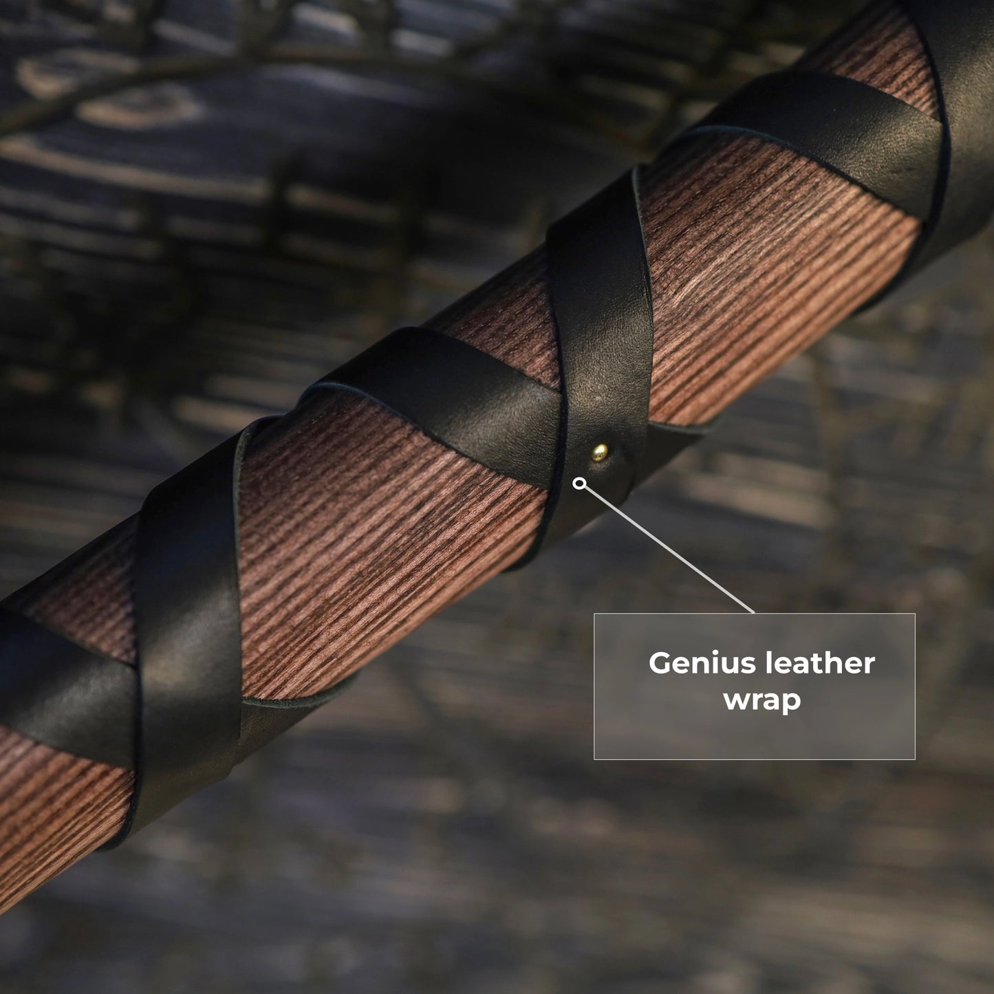 Close up of a wooden axe handle, wrapped with strips of black leather.