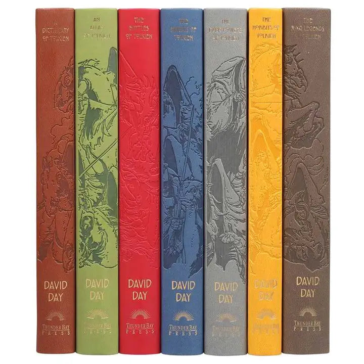 Seven hardcover books lined up side by side with their spines visible. Each book is a different color, with a drawing of creatures from the Lord of the Rings series spanning all seven books. 