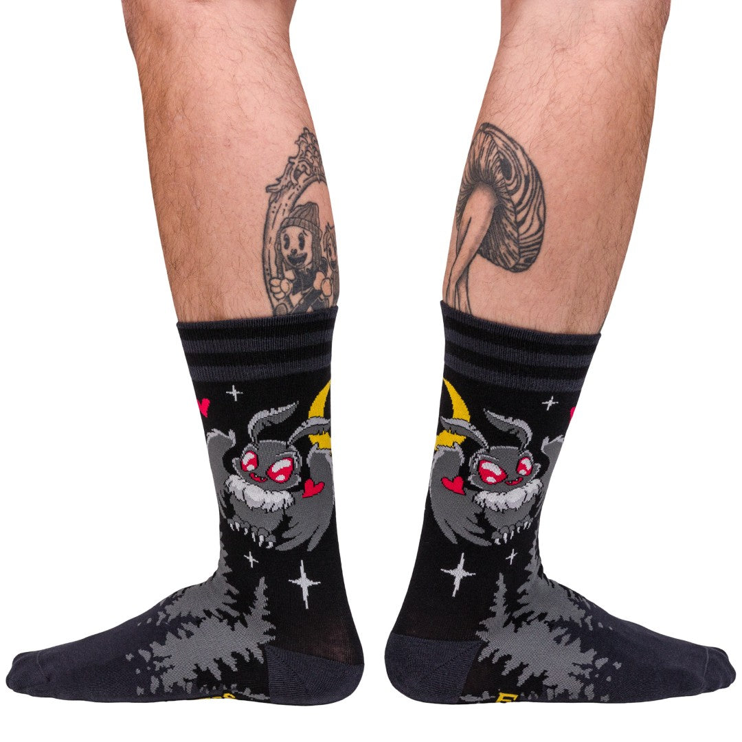 Black socks with a cartoon character design worn by a person on a white background