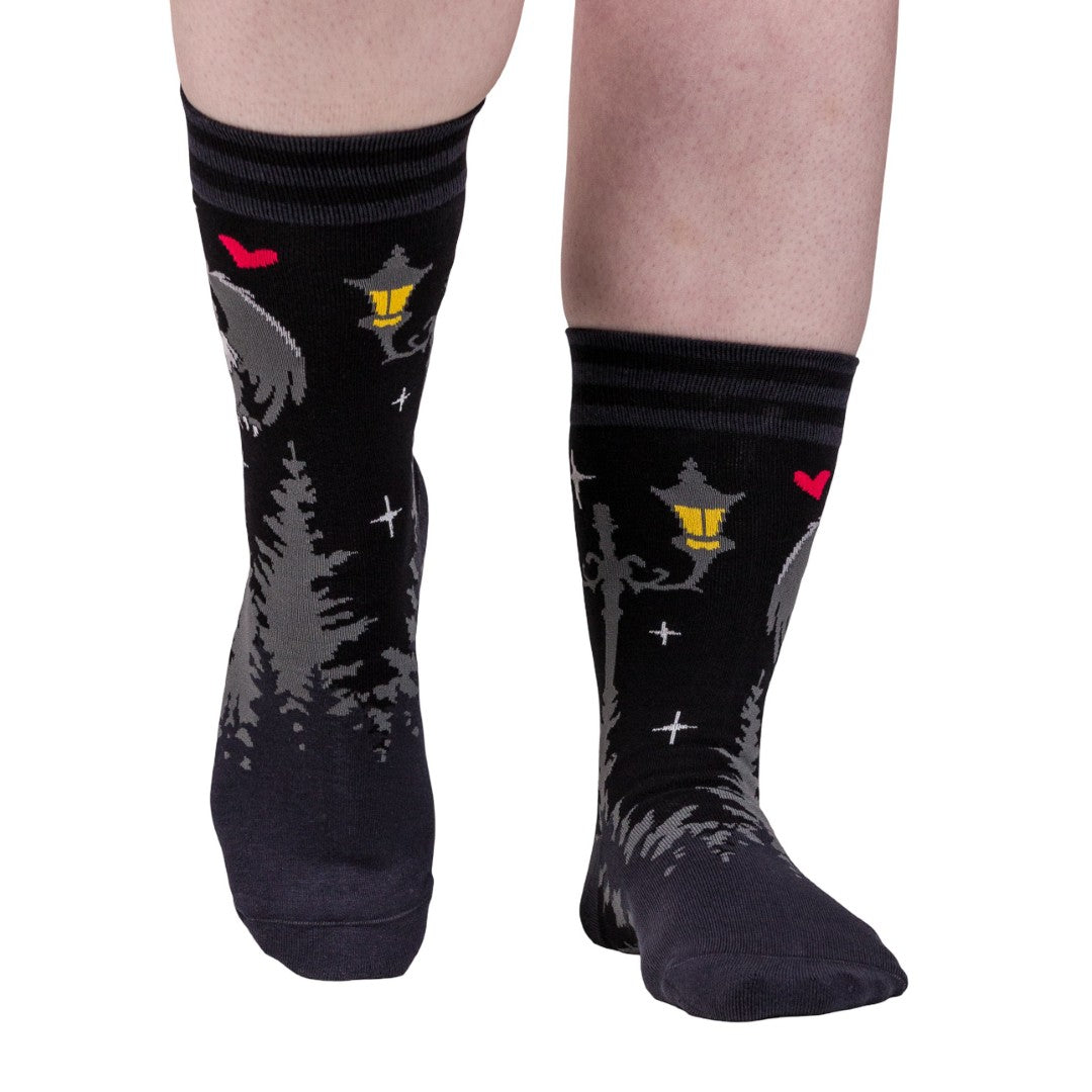 Black socks with cat designs worn by a person on a white background