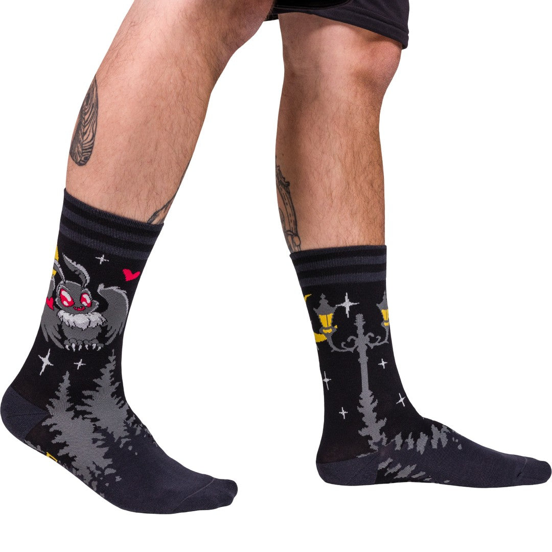 Black socks with cat designs worn by a person on a white background