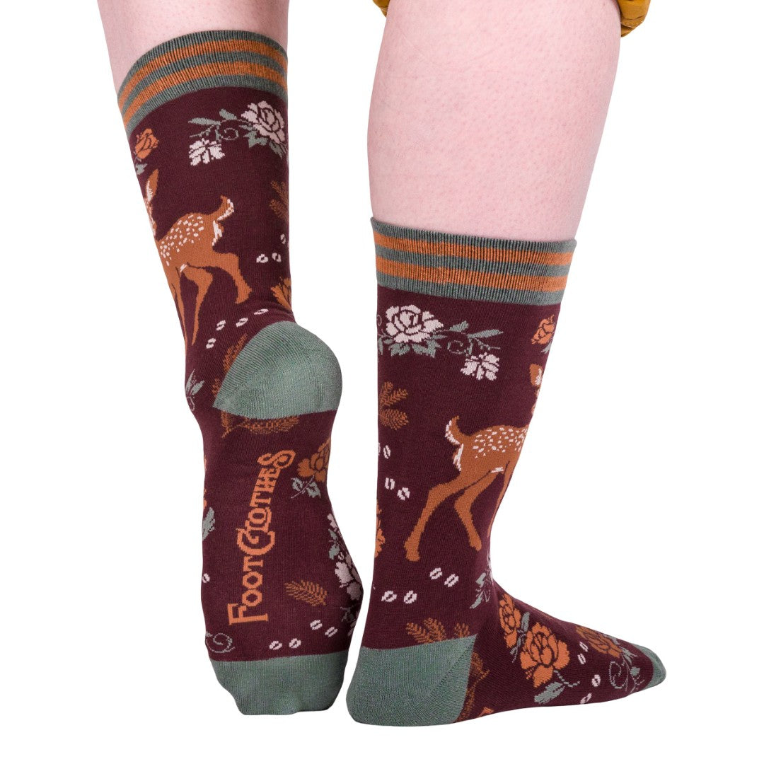 Maroon socks with deer and floral pattern worn by a person on a white background