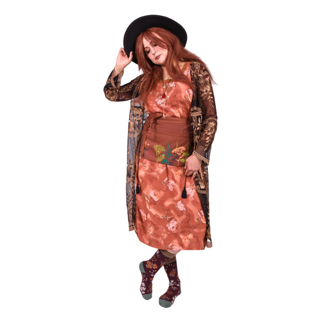 Woman wearing a floral dress and patterned cardigan on a white background