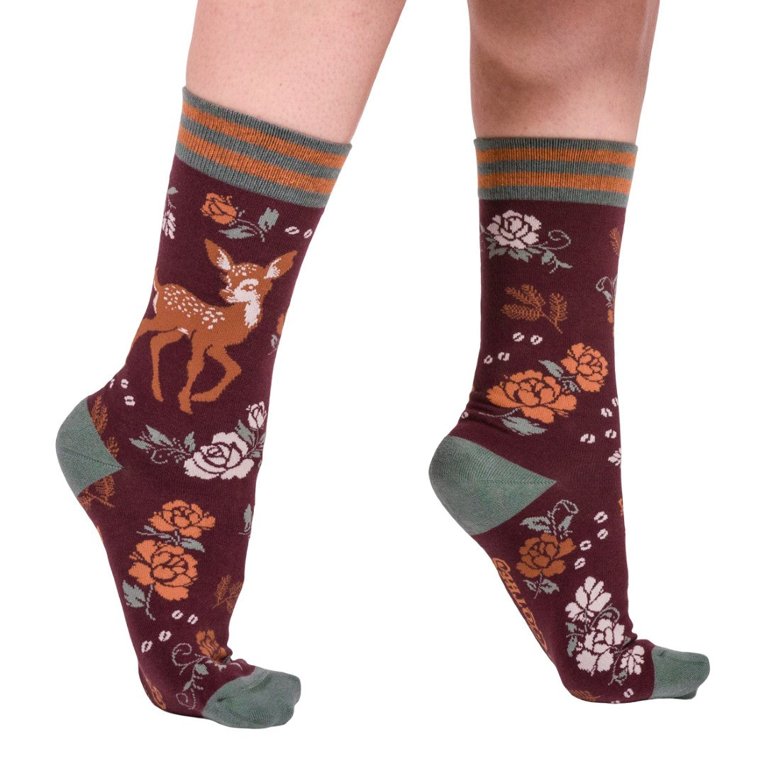 Maroon socks with deer and floral patterns worn by a person on a white background