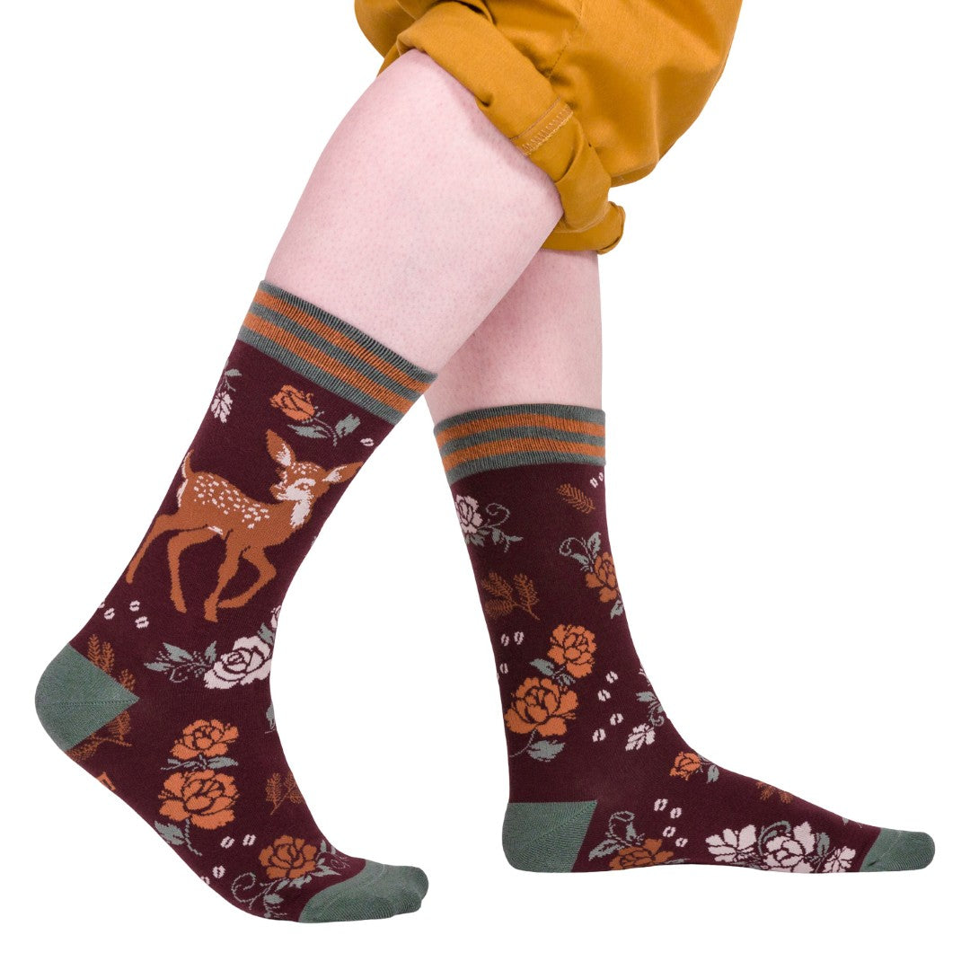 Knee-high socks with deer and floral pattern worn by a person on a white background
