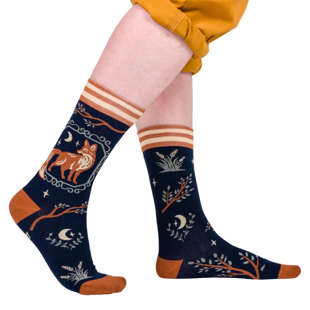 Navy blue socks with fox and nature patterns worn by a person on a white background