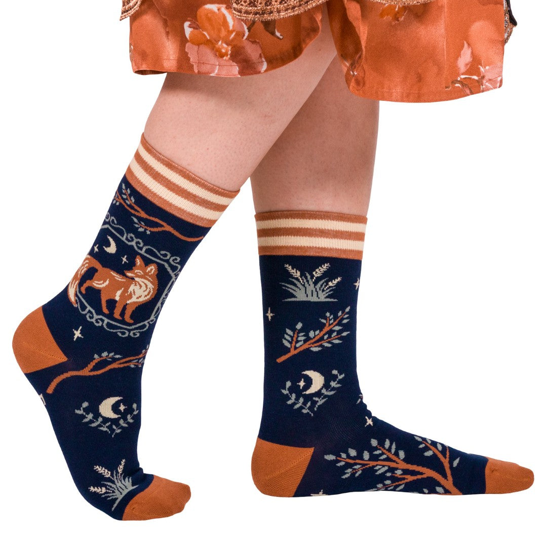 Navy blue socks with orange and white patterns worn by a person in an orange dress.