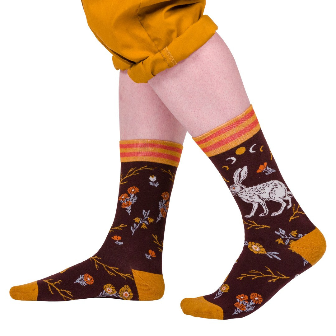 Crew socks with rabbit and floral pattern worn by a model in yellow pants.
