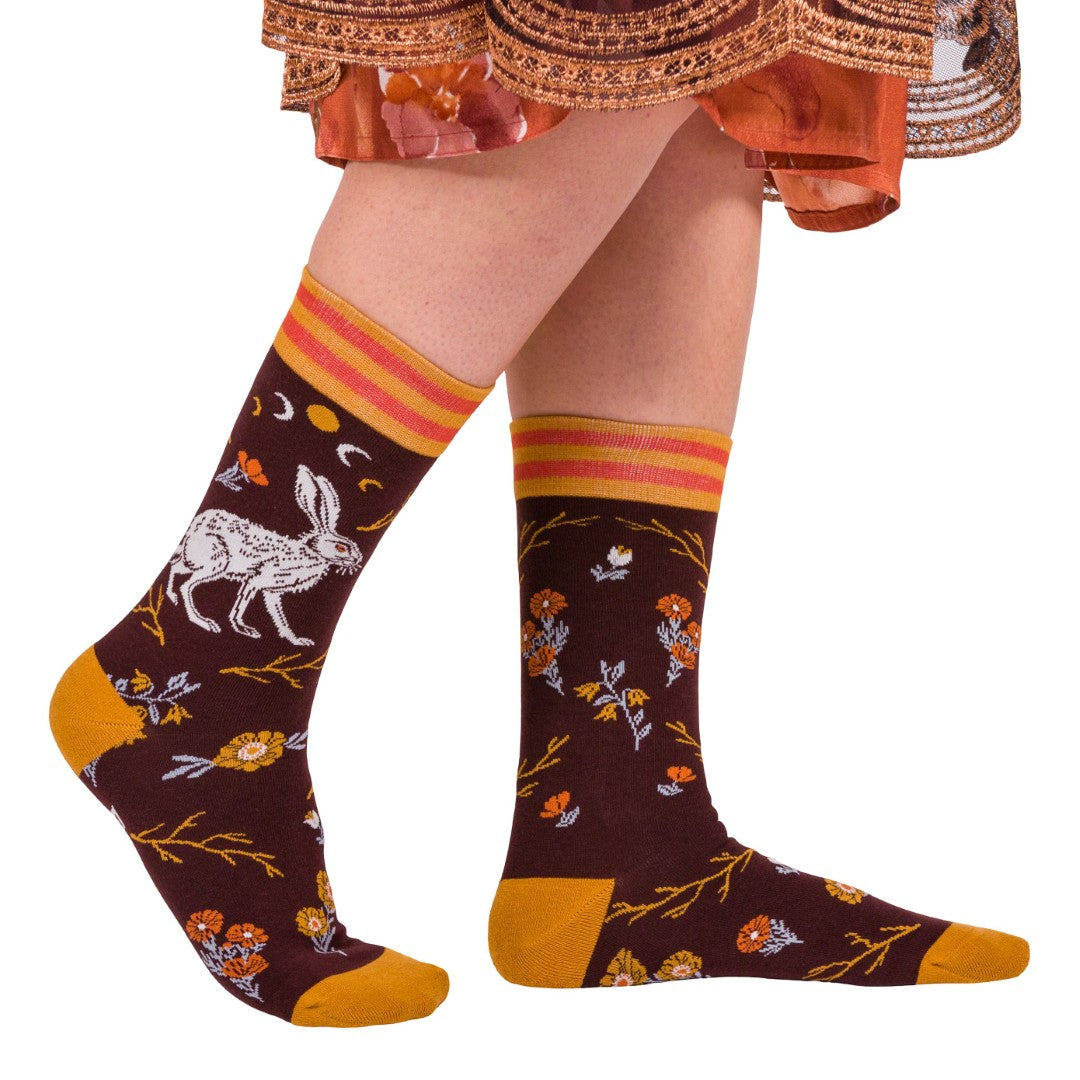 Patterned socks with floral and animal designs worn by a person on a white background