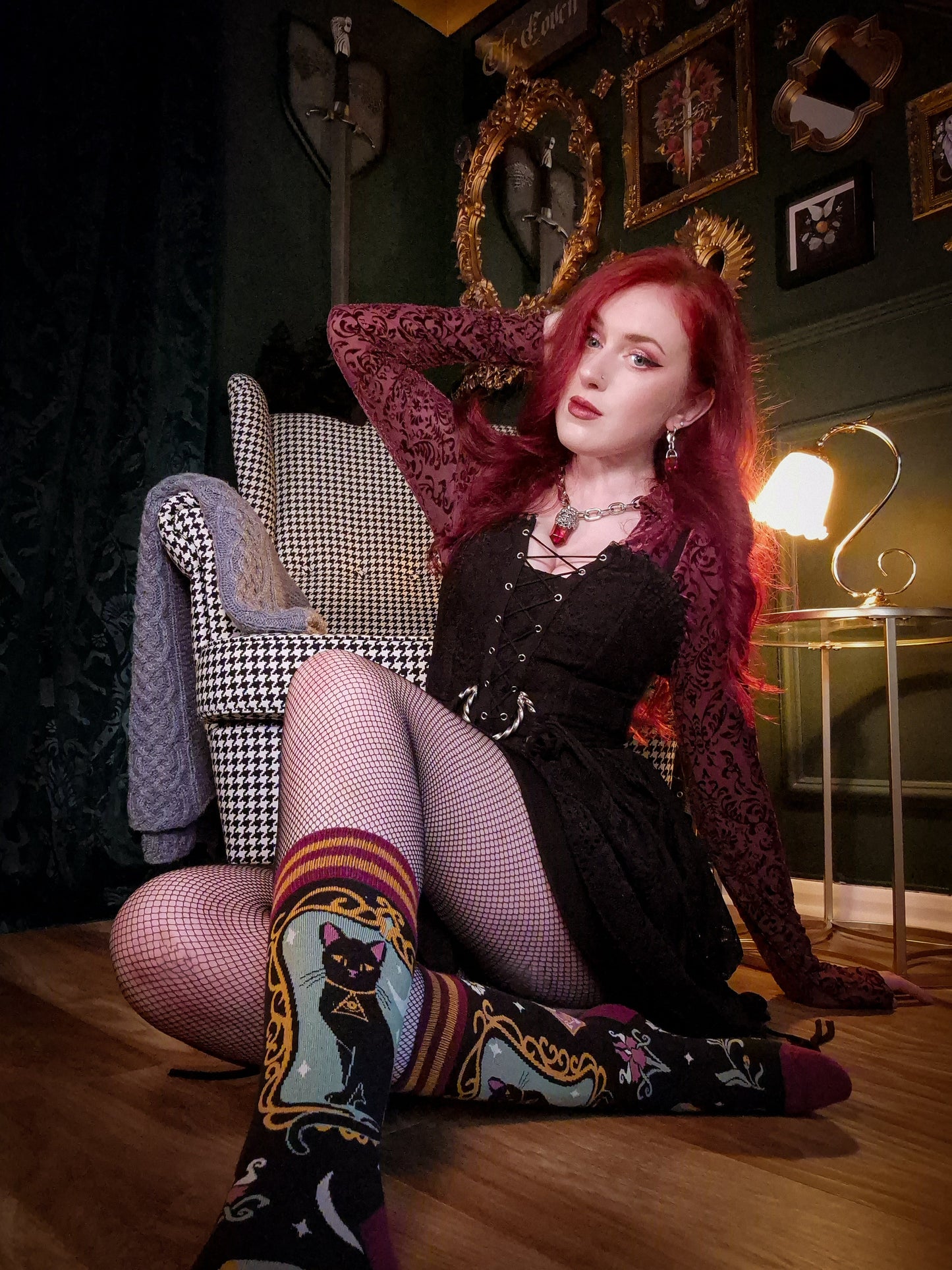 Woman with red hair sitting on a checkered chair in a stylish room.