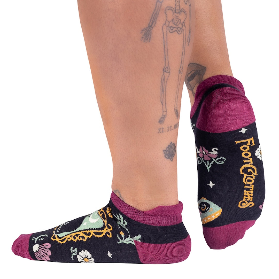 Person wearing black socks with colorful designs and 'Four Corners' text on a white background