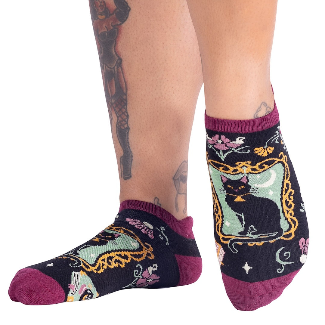 Socks with black cat design worn by a person on a white background