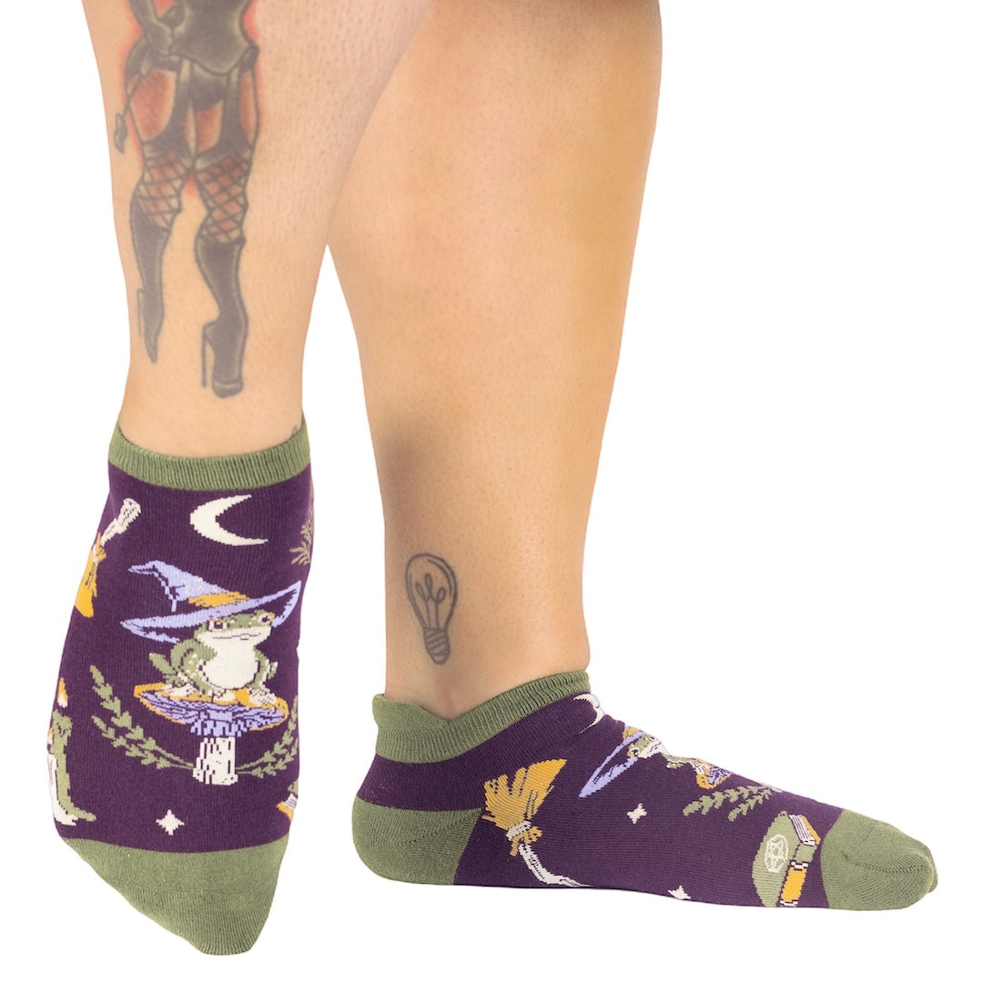 Purple socks with witch-themed design worn by a person on a white background