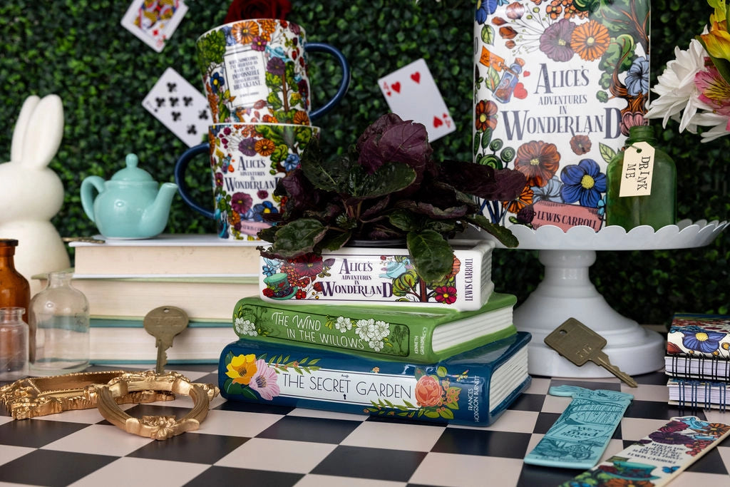 Decorative setup with books, plants, and Alice in Wonderland-themed items on a checkered surface.