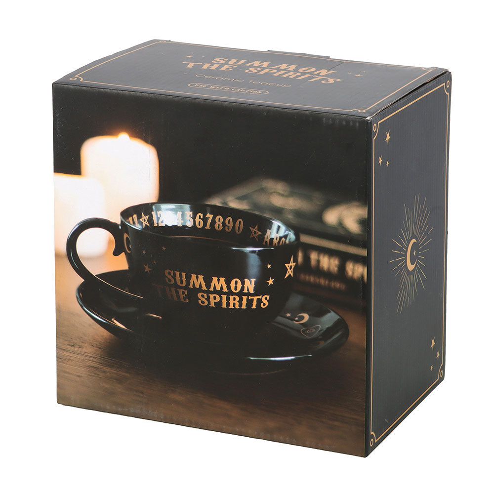 Black mug and saucer set with 'Summon the Spirits' text in gold, displayed in a decorative box.