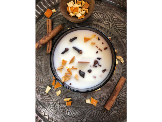 Cinnamon roll candle with decorative elements on a textured surface