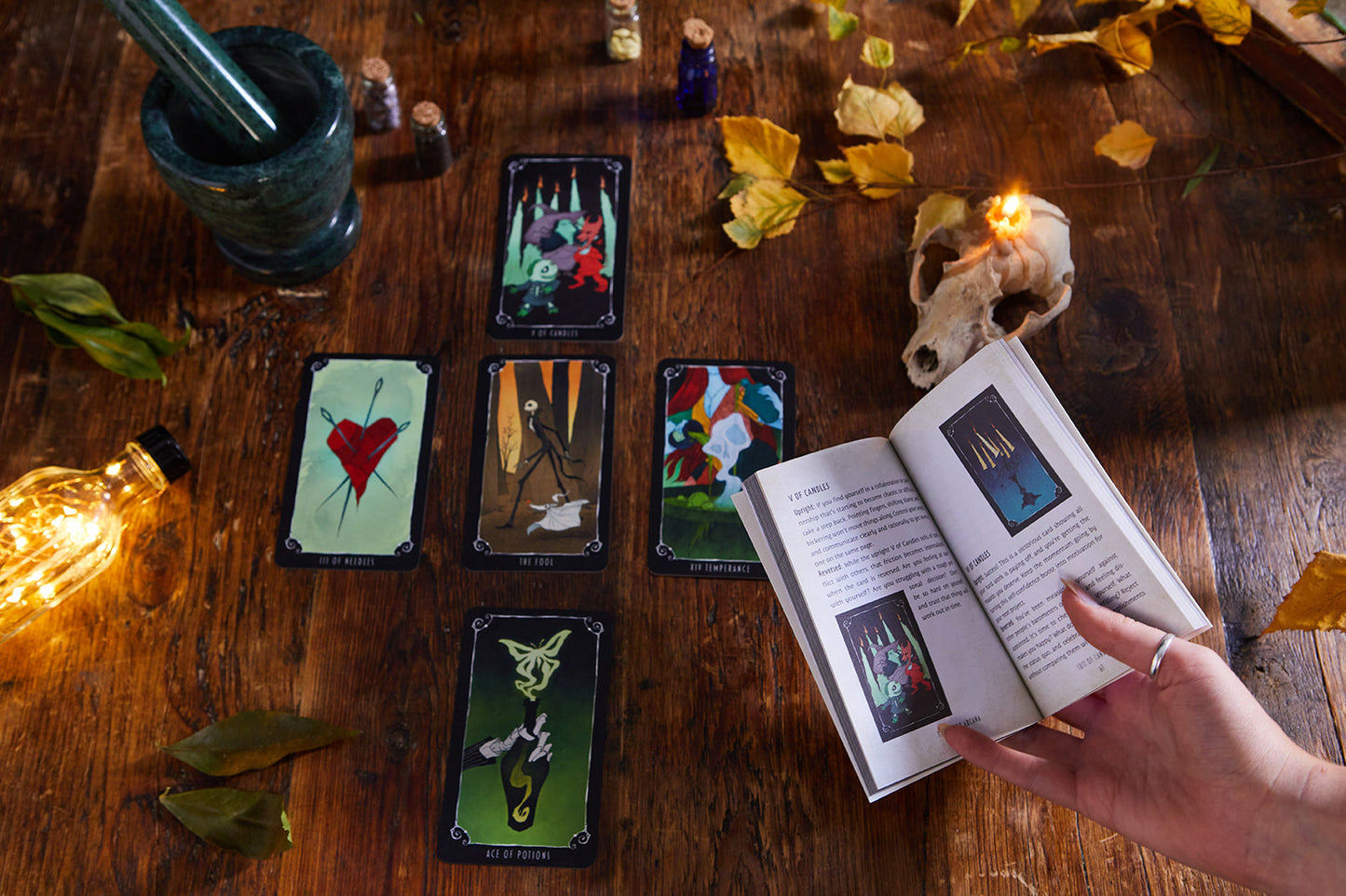 Tarot cards on a wooden table with a book and candles, creating a mystical atmosphere.
