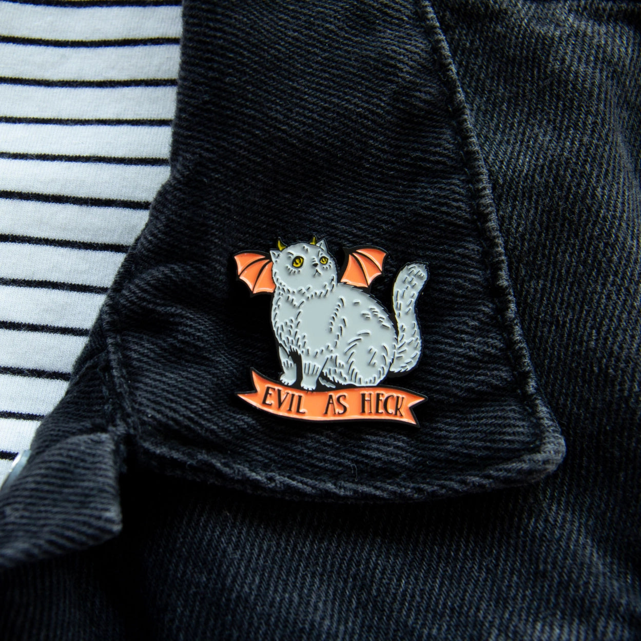 Load image into Gallery viewer, A grey cat with orange bat wings and yellow horns, attached to a dark denim collar. Under the cat is an orange ribbon with black text saying &amp;quot;Evil as heck.&amp;quot;
