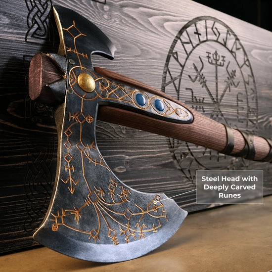 A wooden axe, styled after the one used by Kratos in the "God of War" video games, on a wooden table. The blade has runes inscribed in the flat edge. Next to the axe is a wooden case with a Norse compass design on the front.
