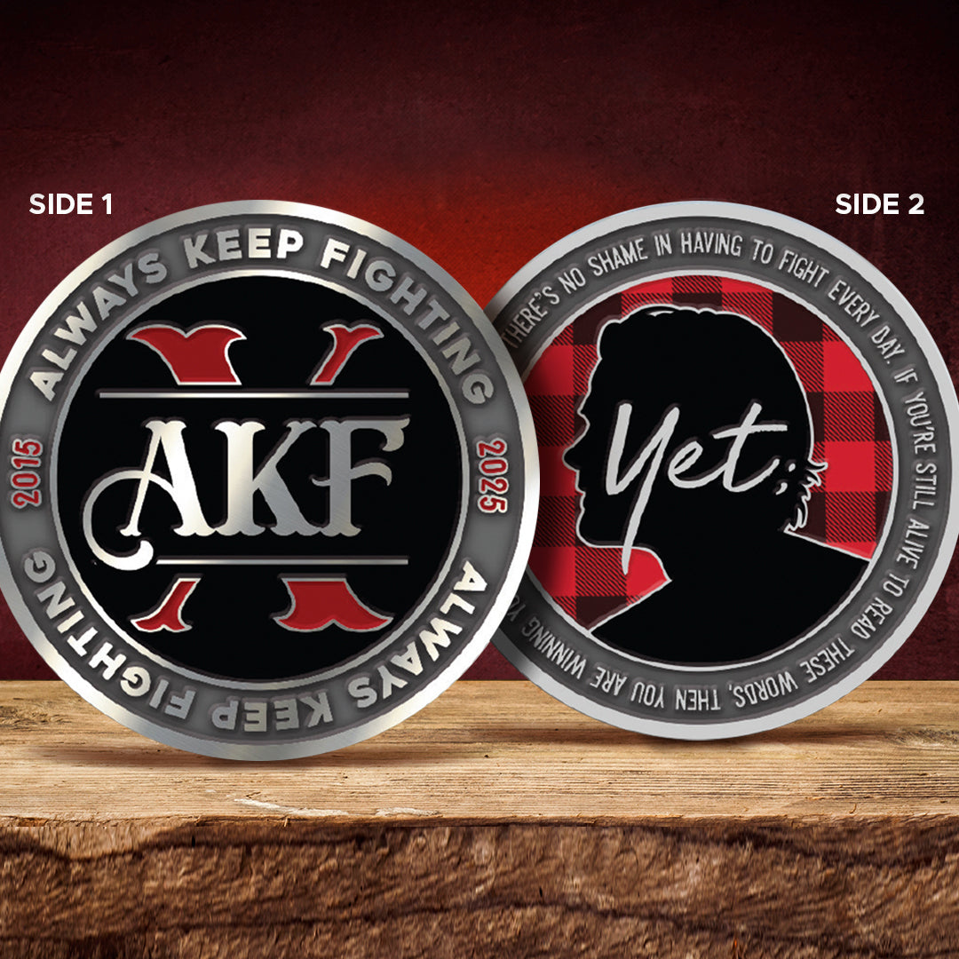 Two sides of a coin with AKF branding and motivational text on a wooden surface.
