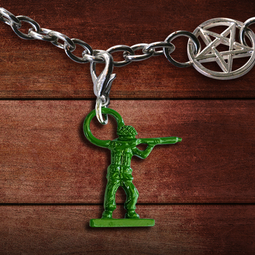 A green army man toy charm on a silver chain, against a wooden background. At the top is a charm in the shape of the anti-possession symbol..