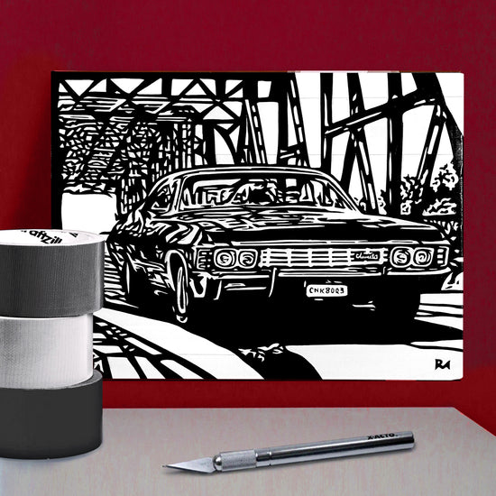 A black and white poster against a dark red wall. The poster depicts a black chevy impala driving over a metal bridge. Next to the poster are rolls of colored duct tape and cutting tools.
