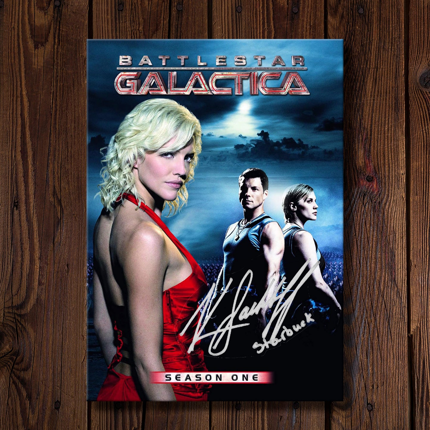 DVD cover of 'Battlestar Galactica' season 1 on a wooden surface. On the cover is Katee Sackhoff's autograph