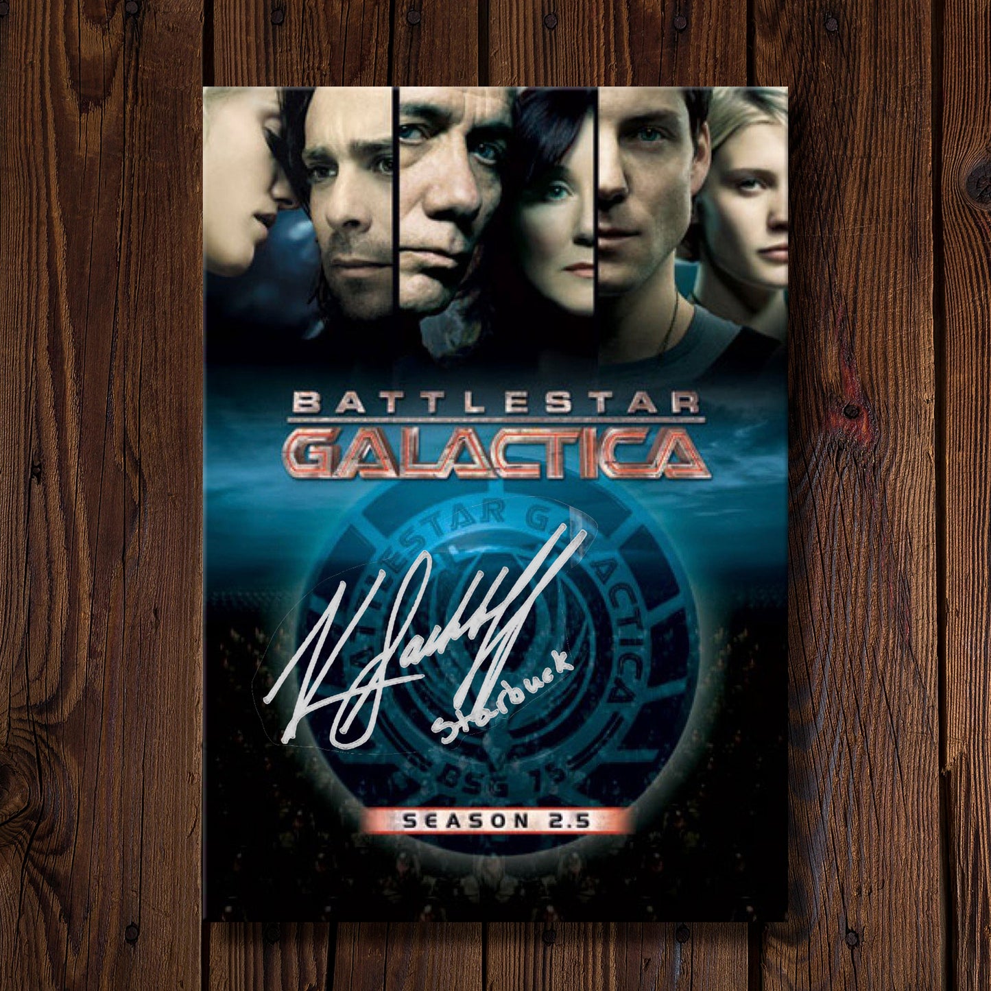 DVD cover of 'Battlestar Galactica' season 2.5 on a wooden surface. On the cover is Katee Sackhoff's autograph