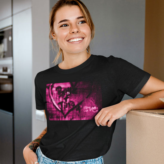 A female model wearing a black t-shirt. On the front of the T-shirt is a pink and black spraypaint design with a heart that says "Better & Tine 4 Ever."  Behind the model is a modern kitchen.