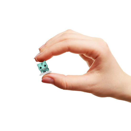 Close up image of a model's hand holding a miniature Funko pop figure, depicting the character Bulbasaur.