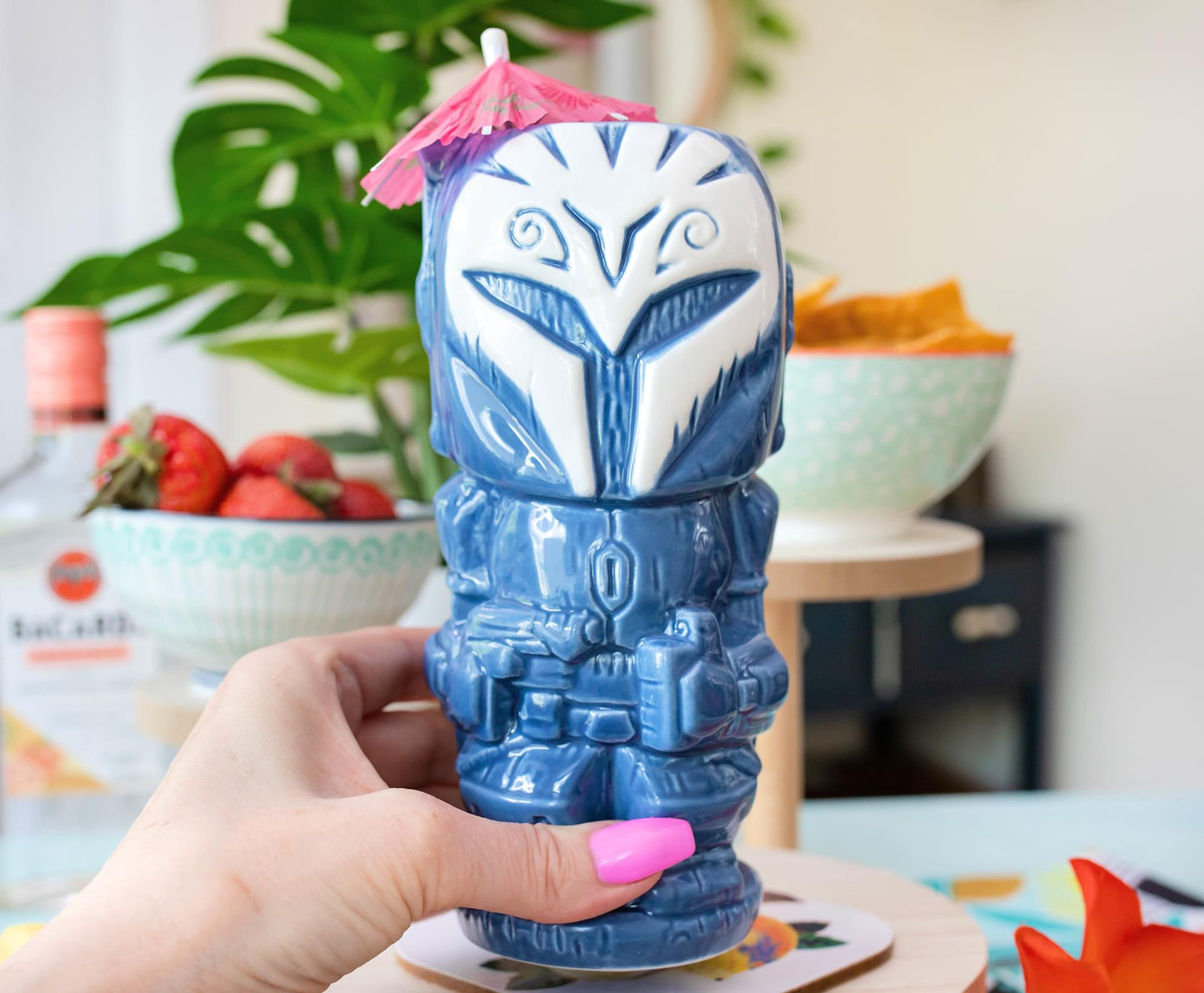 A model's hand holding a blue tiki mug depicting the Mandalorian character Bo Katan.